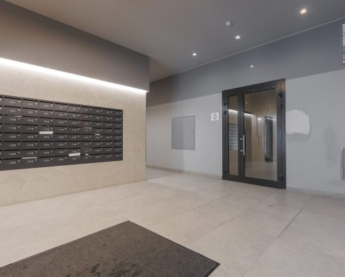 A modern apartment building lobby with clean tile floors, a wall of numbered mailboxes, and a glass entrance door, highlighting residential condominium and multi-family building janitorial maintenance services.